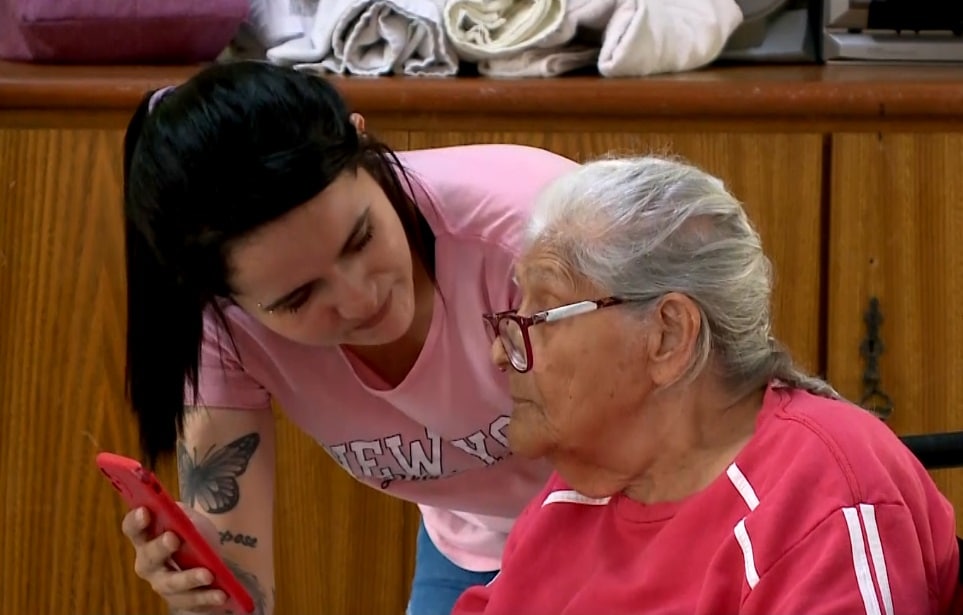 Imagem de paciente com parkinson junta de sua cuidadora.