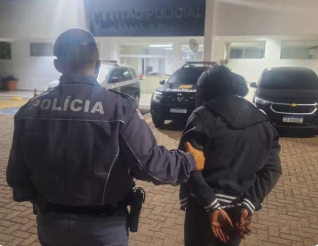 Policial levando mulher suspeita até a delegacia.