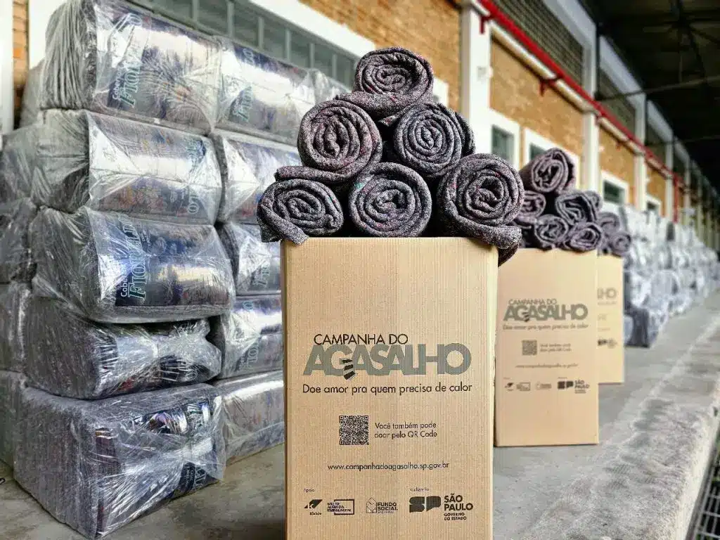 Imagem de cobertores em cima de uma caixa de papelão onde ficam as doações