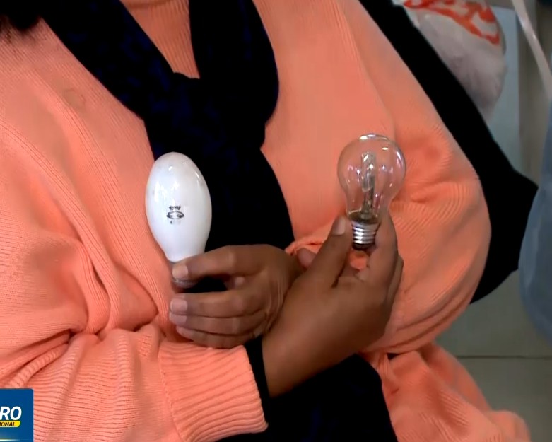 Mulher segurando duas l&acirc;mpadas.