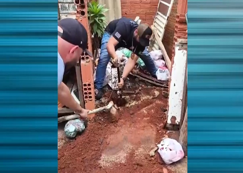 Policiais encontrando o corpo no terreno.