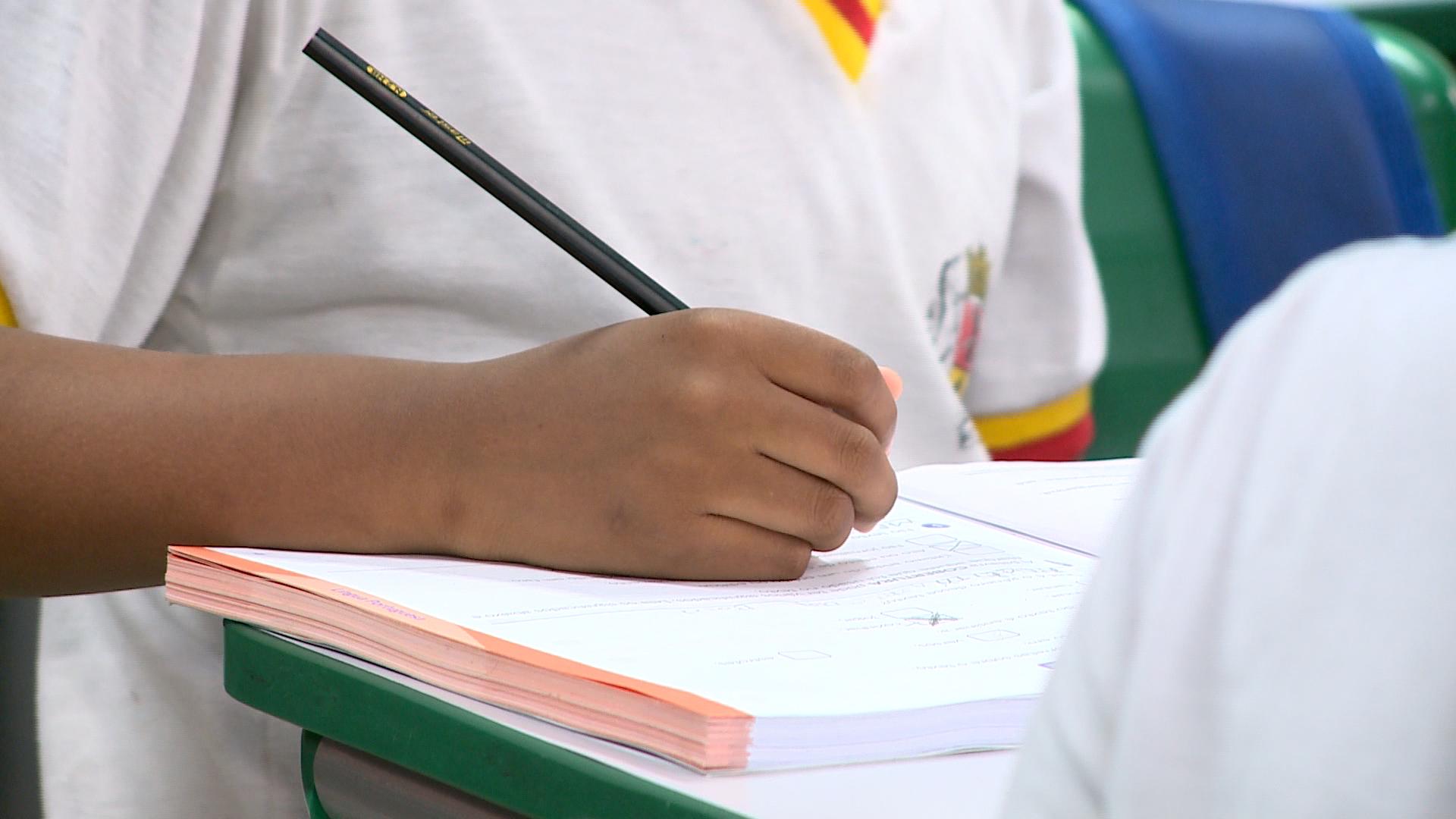 Menino escrevendo no caderno.