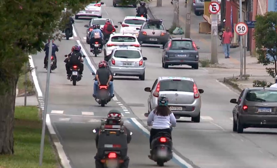 Carros e motos trafegando na rua.