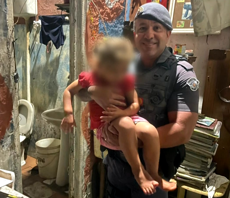 Imagem de Policial Militar com a crian&ccedil;a no colo.