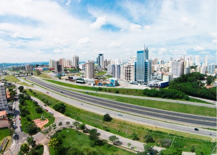Imagem de rodovia e cidade ao fundo.